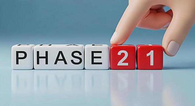 Conceptual hand placing a red block with the number 2 next to the blocks spelling PHASE on a reflective blue surface symbolizing the transition to phase 2 representing progress development and strateg photo