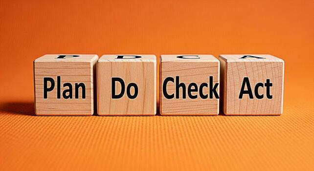 Wooden blocks displaying Plan Do Check Act on an orange surface illustrating the iterative fourstep management method used in business for the control and continuous improvement of processes and produ photo