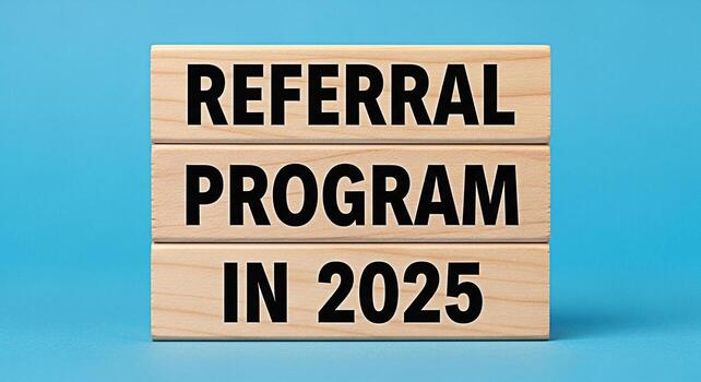 Wooden blocks stacked on a blue surface displaying Referral Program in 2025 symbolizing a futureoriented business strategy and a proactive approach to growth through recommendations and partnerships photo