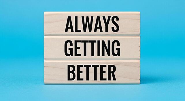 Stack of wooden blocks displaying the message Always Getting Better against a vibrant blue background symbolizing continuous improvement positive mindset and the pursuit of excellence in personal and photo