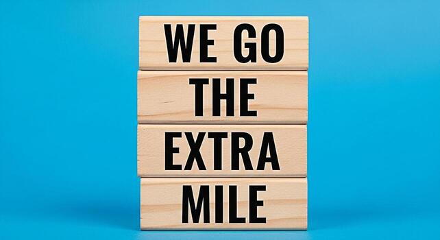 Wooden blocks stacked on a blue background displaying the message We go the extra mile representing dedication commitment and exceeding expectations in a bright and optimistic setting symbolizing succ photo