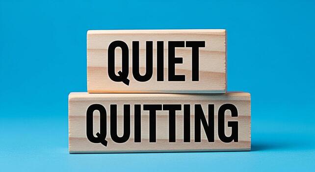 Wooden blocks displaying Quiet Quitting on a bright blue background representing the concept of disengagement and reduced effort in the workplace symbolizing a passive approach to job dissatisfaction photo