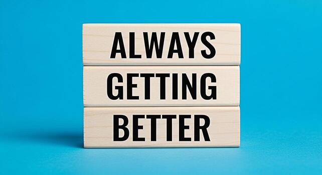 Stack of wooden blocks displaying the motivational phrase Always Getting Better against a vibrant blue background symbolizing continuous improvement and a positive mindset in business and personal dev photo