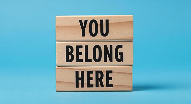 Wooden blocks stacked on a blue surface displaying the message You Belong Here creating a welcoming and inclusive atmosphere symbolizing acceptance and community in a simple and direct manner photo