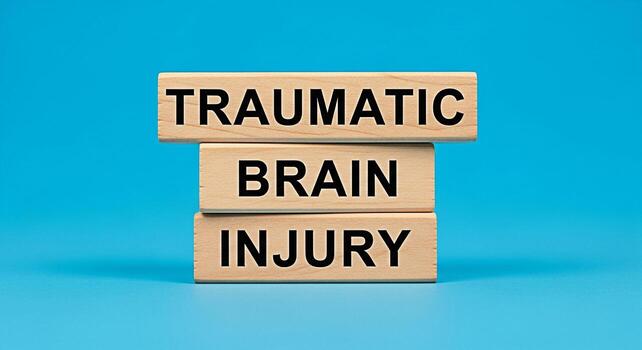 Wooden blocks displaying Traumatic Brain Injury on a blue background emphasizing the serious nature of head trauma and the need for awareness and support for those affected by brain injuries promoting photo