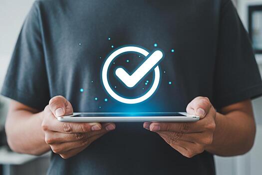 Person holding a tablet displaying a glowing check mark in a bright modern setting symbolizing approval success and digital confirmation with a focus on technology and positive outcomes photo