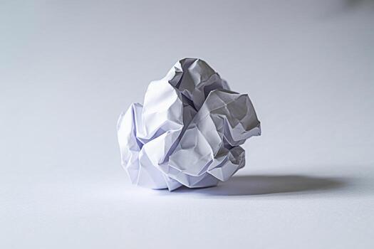 Crumpled white paper ball resting on a clean white surface symbolizing frustration creative block and the iterative process of brainstorming and problemsolving in a minimalist setting photo