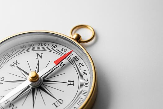 Classic golden compass pointing north on a white surface symbolizing navigation exploration and guidance evoking a sense of adventure precision and the pursuit of new horizons in a minimalist setting photo