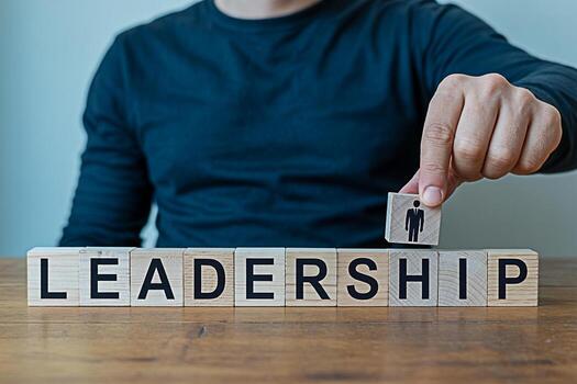 hombre agregando un de madera bloquear con un persona icono a el palabra liderazgo espelta fuera con bloques en un de madera mesa simbolizando edificio fuerte liderazgo habilidades y un exitoso negocio equipo en un corporat foto