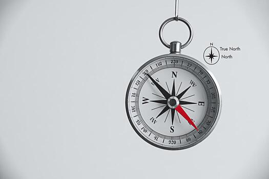 Hanging compass pointing south in a studio setting symbolizing guidance exploration and the importance of direction with a minimalist aesthetic and focus on precision and navigational tools photo