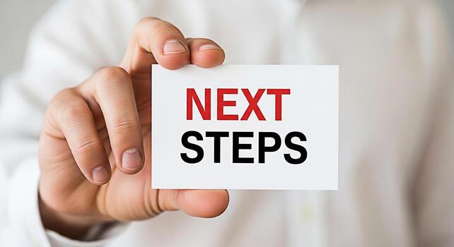 Closeup of a hand holding a card with the text Next Steps in a bright neutral environment symbolizing progress planning and a clear path forward in business and personal development photo