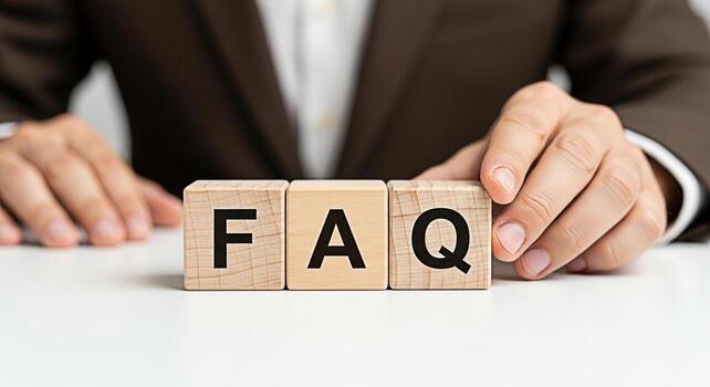 Professional businessman arranging wooden blocks spelling FAQ on a white desk in a bright office symbolizing frequently asked questions and providing helpful information and customer support photo