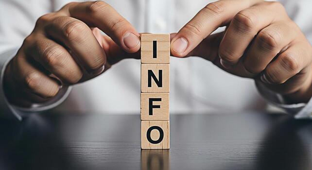 Person arranging wooden blocks spelling INFO on a dark wooden table conveying a message of information knowledge and data with a focus on clarity and accessibility in a modern business setting photo