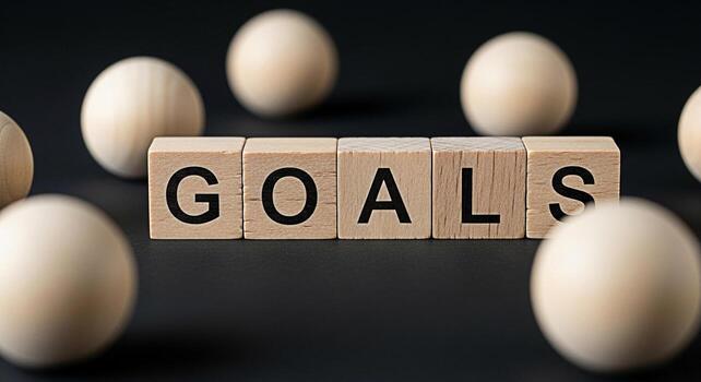 Wooden blocks spelling GOALS surrounded by wooden spheres on a dark surface representing ambition and the pursuit of objectives symbolizing motivation and achievement in a minimalist setting photo