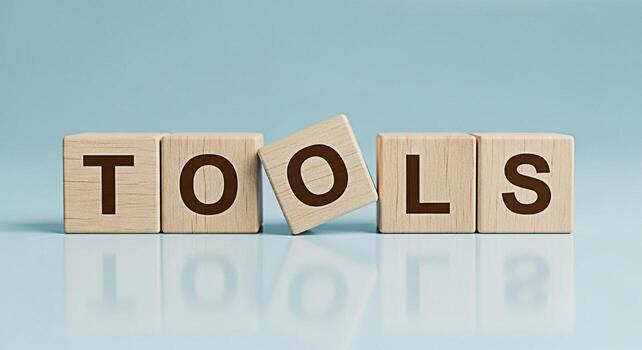 Wooden blocks spelling TOOLS on a reflective surface symbolizing resources and equipment in a studio setting conveying a message of utility readiness and the importance of having the right instruments photo