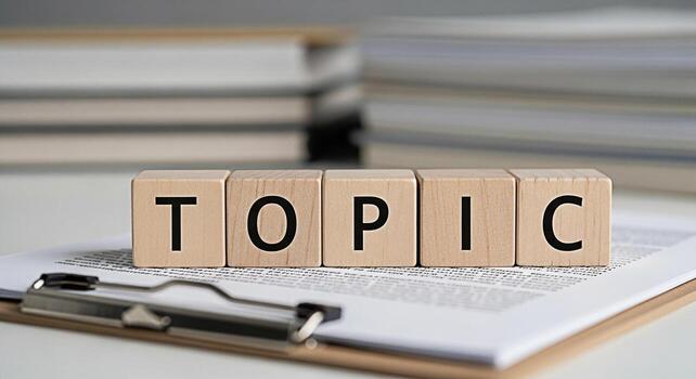 Wooden blocks spelling TOPIC rest on a clipboard with documents in a bright organized office setting representing focus discussion and the importance of clear communication in business and education photo