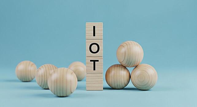 Wooden blocks spelling IOT surrounded by wooden spheres on a light blue background representing the concept of the Internet of Things and its growing influence on modern technology and interconnected photo