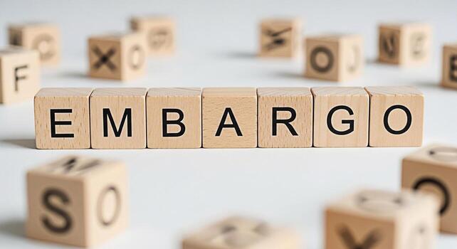 Wooden blocks spelling EMBARGO on a white surface surrounded by other lettered blocks conveying a sense of restriction control and the importance of adhering to rules and regulations in business and c photo