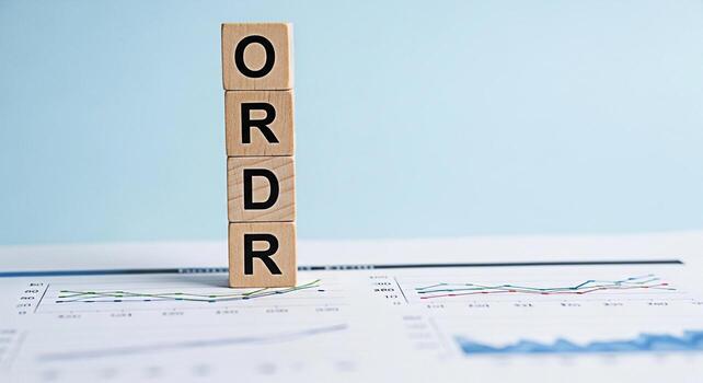 Wooden blocks spelling ORDER placed on financial charts in a bright clean office environment symbolizing organization structure and systematic approach to business and financial success photo