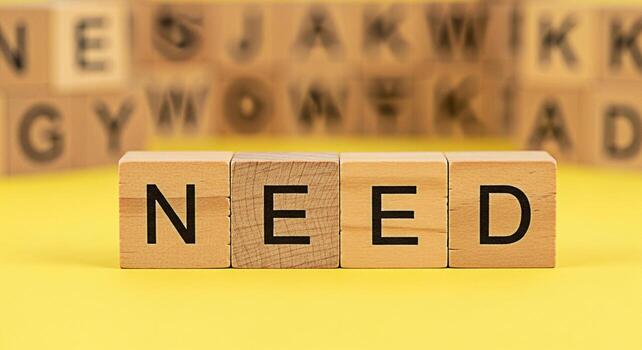 Wooden blocks spelling NEED on a bright yellow background conveying a sense of urgency and importance highlighting essential requirements and necessities in a simple impactful way emphasizing the conc photo