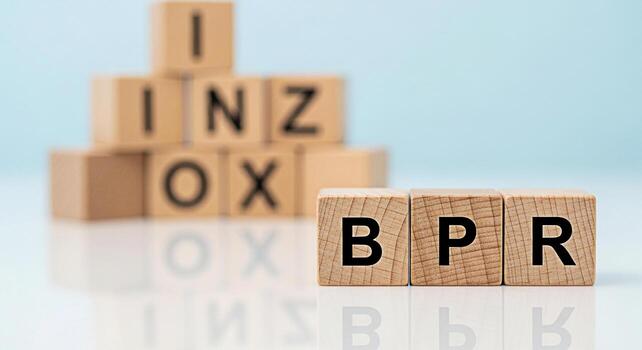 Wooden blocks displaying the acronym BPR Business Process Reengineering on a white reflective surface against a soft blue background conveying a message of business strategy and organizational change photo