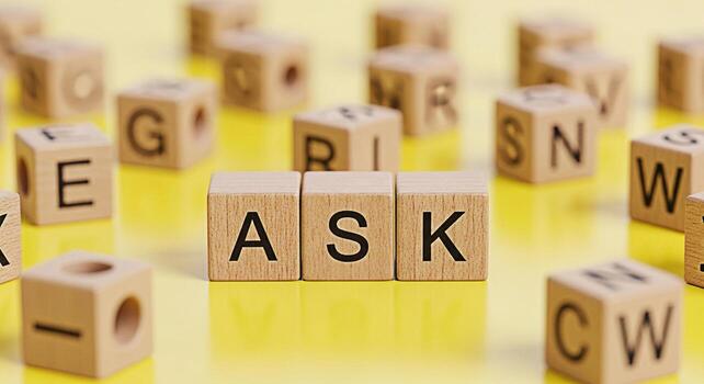 Wooden blocks spelling ASK on a bright yellow surface surrounded by other lettered blocks creating a playful and educational atmosphere symbolizing curiosity learning and the importance of questioning photo