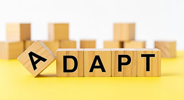 Wooden blocks spelling ADAPT on a yellow surface symbolizing flexibility and resilience in a changing environment conveying a message of business agility and the importance of embracing change for suc photo