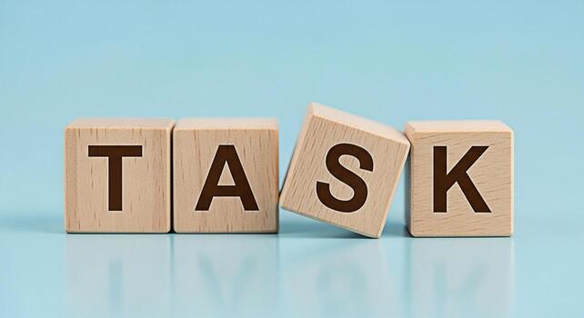 Wooden blocks spelling TASK on a light blue surface representing project management and the importance of completing assignments conveying a sense of organization and focus in a minimalist setting photo