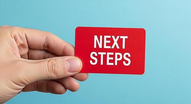 A hand holding a red card with the words Next Steps against a light blue background symbolizing planning and forward movement representing a clear path to achieve goals and objectives with a positive photo
