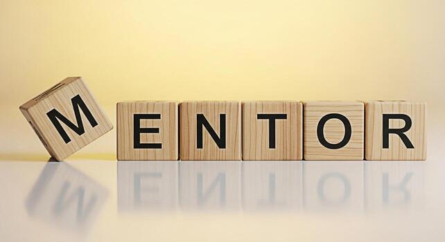 Wooden blocks spelling MENTOR on a reflective surface symbolizing guidance and support in a bright optimistic setting conveying a message of mentorship learning and positive influence for career devel photo