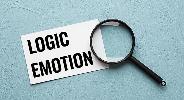 Closeup of a magnifying glass examining a card with the words Logic and Emotion on a textured blue background representing the concept of decisionmaking analysis and the balance between reason and fee photo