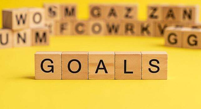 Wooden blocks spelling GOALS arranged on a bright yellow surface symbolizing aspiration and determination with blurred letter blocks in the background creating a motivational and focused atmosphere fo photo