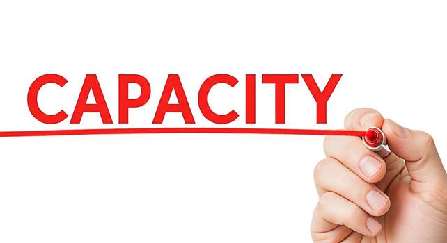 Hand underlining the word Capacity in bold red letters on a white background symbolizing potential ability and the measurement of limits in business technology or personal growth with a sense of impor photo