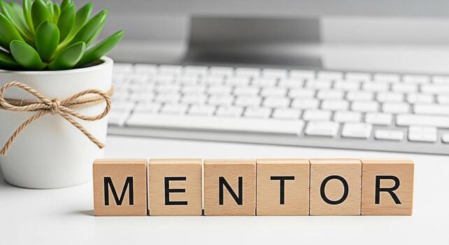 Wooden blocks spelling MENTOR on a white desk next to a potted succulent and computer keyboard symbolizing guidance support and professional development in a modern office environment photo