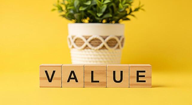 Wooden blocks spelling VALUE on a bright yellow surface with a potted plant in the background symbolizing importance worth and the essence of quality in a minimalist and vibrant setting photo