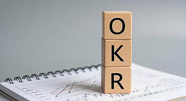 Wooden blocks displaying OKR resting on a notebook with a graph symbolizing objectives and key results in a business setting conveying a sense of strategic planning and performance measurement photo