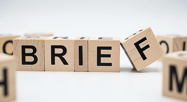 Wooden blocks spelling BRIEF on a white surface with one block slightly tilted conveying a sense of urgency and the importance of concise communication in a professional and efficient manner photo