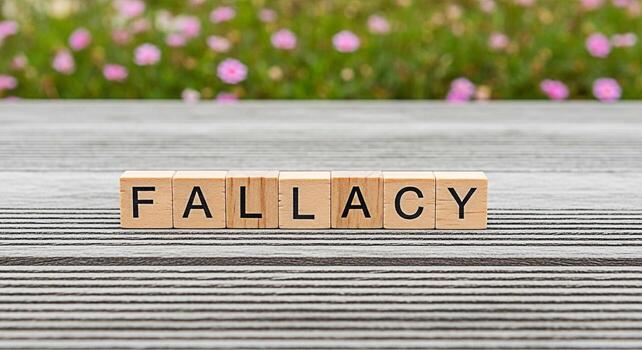 Wooden blocks spelling FALLACY on a striped wooden surface in a garden setting representing a logical error flawed reasoning and the importance of critical thinking in identifying deceptive arguments photo