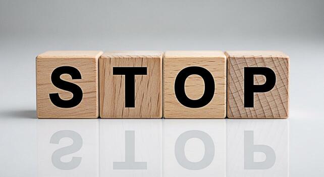 Wooden blocks spelling out STOP on a reflective surface conveying a message of caution and prevention in a clean minimalist setting emphasizing the importance of halting actions for safety and awarene photo