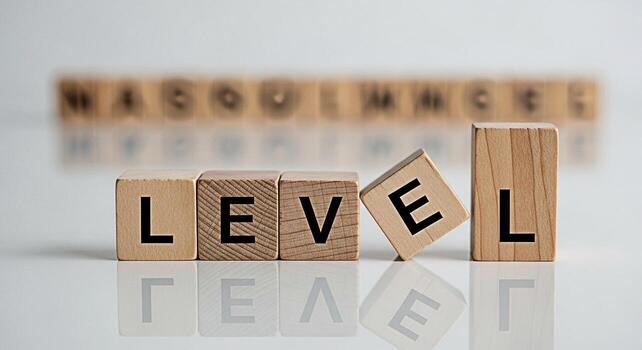 Wooden blocks spelling out the word LEVEL on a reflective surface with a blurred background of more blocks conveying a sense of achievement progress and the challenges of reaching new heights photo