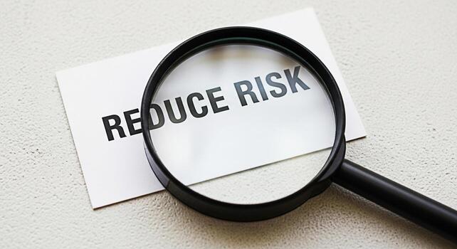 Magnifying glass focusing on a card with the words Reduce Risk on a textured surface symbolizing careful examination and strategic planning for risk management and mitigation in a business context photo