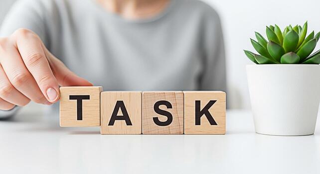 Person arranging wooden blocks spelling TASK on a white desk in a bright office symbolizing focus organization and the successful completion of goals with a sense of accomplishment and productivity photo