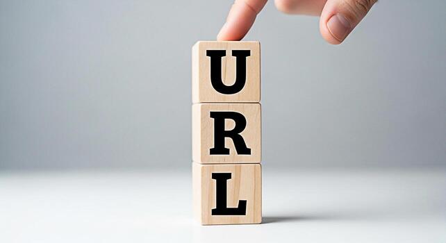 A finger gently touches wooden blocks stacked vertically spelling out URL on a clean white surface symbolizing internet addresses web navigation and the concept of online accessibility with a minimali photo