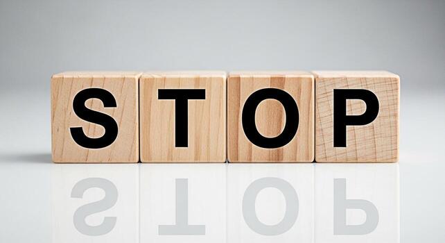 Wooden blocks spelling STOP on a reflective white surface conveying a message of caution and prevention in a clean minimalist setting symbolizing control and the importance of pausing for consideratio photo