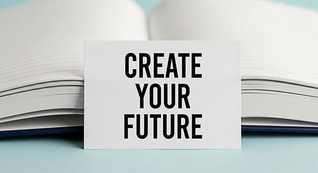 Inspirational message Create Your Future displayed on a white card placed in front of an open notebook on a light blue surface symbolizing motivation planning and a positive outlook for the future photo