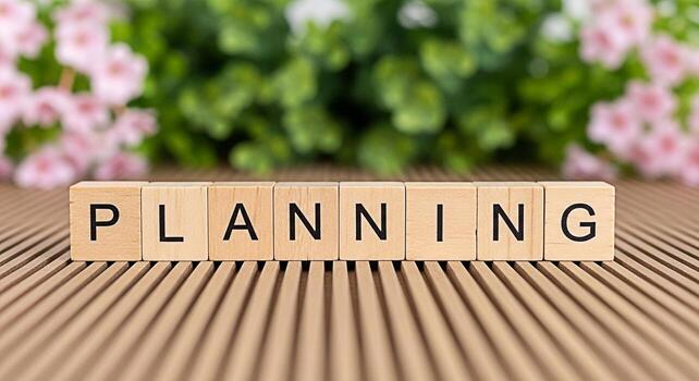 Wooden blocks spelling PLANNING arranged on a striped wooden surface against a soft floral background symbolizing strategic preparation and forwardthinking in a serene and optimistic setting photo