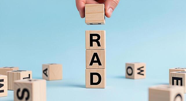 Hand placing a wooden block with the letter R on top of blocks spelling RAD on a light blue surface symbolizing a positive and enthusiastic attitude conveying a message of positivity and excitement photo