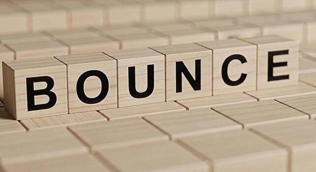 Wooden blocks spelling Bounce resting on a grid of similar blocks conveying a sense of resilience energy and the ability to recover quickly from setbacks in a neutral minimalist setting ideal for moti photo