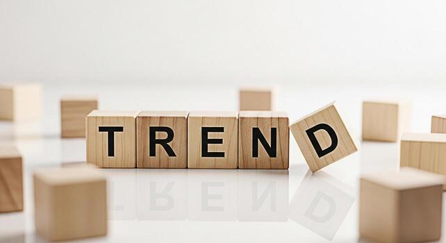 Wooden blocks spelling TREND on a reflective white surface with one block falling representing the dynamic nature of trends and the importance of adapting to change in a modern fastpaced environment photo