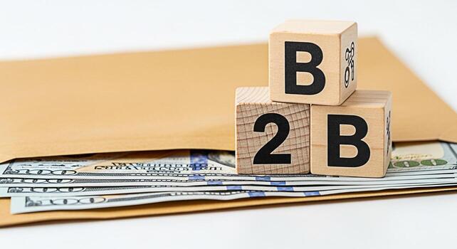 Wooden blocks displaying B2B resting on an envelope filled with US currency symbolizing businesstobusiness transactions and financial success in a clean minimalist setting conveying a sense of prosper photo